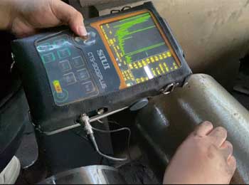 Portable ultrasonic flaw detector being used on a steel surface.