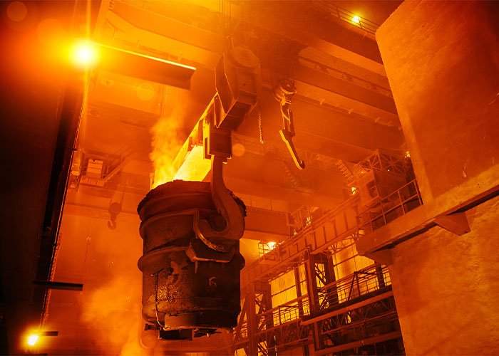 Orange-lit steelmaking or heat-treatment operation with molten or glowing metal.
