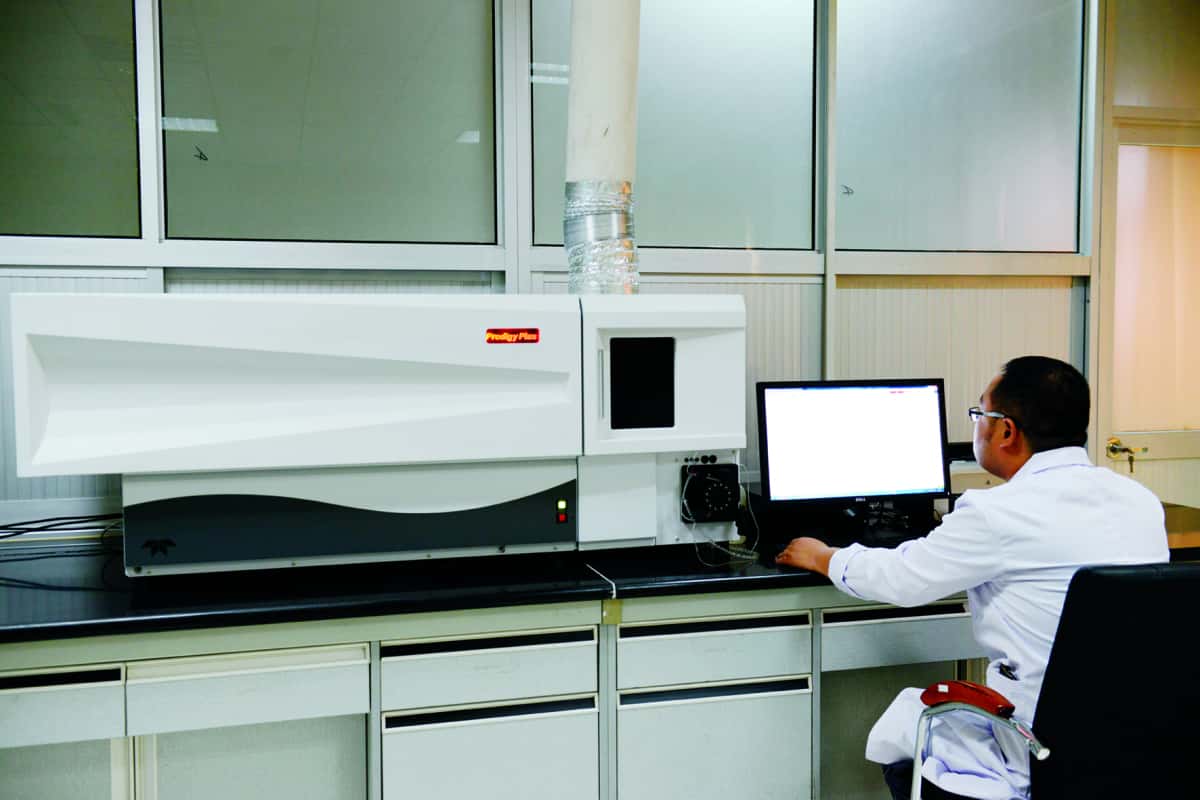 Technician operating a large industrial materials analyzer in a laboratory.